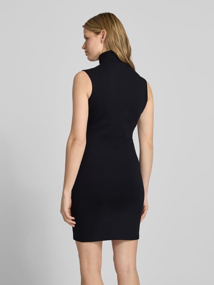 Frauenmodel trägt körpernahes Damen Jerseykleid aus Baumwoll-Mix Modell 'NUZIPPO_B' von Hugo Blue, Optik: Unifarben, Mini-Länge, Hochgeschlossen, Kontraststreifen, Label-Stitching, kurzer Reißverschluss, ohne Ärmel, Materialverarbeitung: Jersey, Ganzkörperansicht Rückansicht.