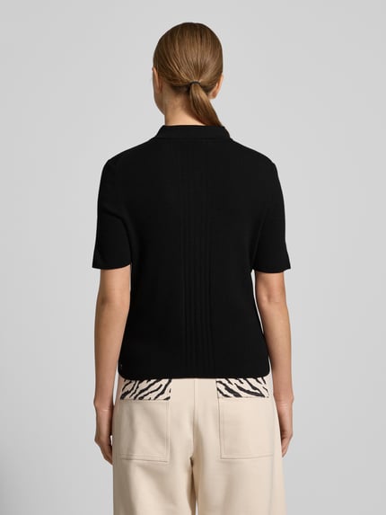 Frauenmodel trägt Strickpullover mit Kaschmir-Anteil von Marc Cain in Schwarz, Slim Fit, kurzärmelig, Polokragen, Rückansicht, Ganzkörperansicht.