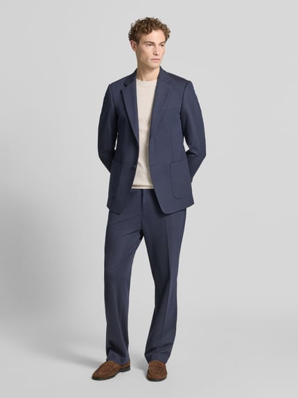 Männermodel trägt Regular Fit Stoffhose aus Viskose-Mix Modell 'ISCOVE' von Tiger Of Sweden, dunkles Blau, Bundfalten, Ganzkörperansicht von vorne. Kontext: Herren Stoffhose, Tunnelzug, Bundweite bei Größe 50: 42 cm, Innenbeinlänge bei Größe 50: 82 cm.