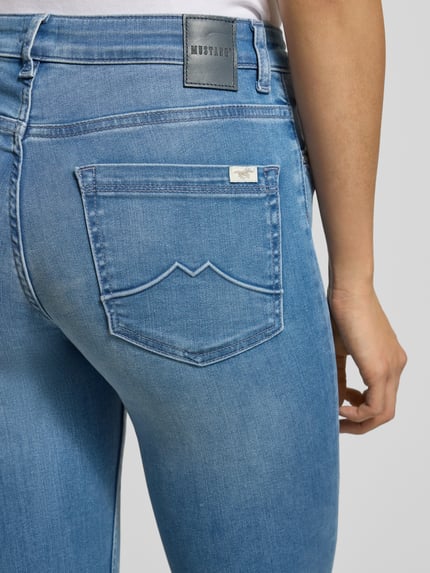 Frauenmodel trägt Flared Jeans mit 5-Pocket-Design von Mustang, hellblauer Baumwoll-Lyocell-Mix mit Stretch, Nahaufnahme Rückansicht.