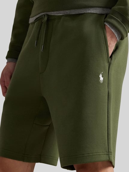 Männermodel trägt Regular Fit Sweatshorts aus Baumwoll-Mix von Polo Ralph Lauren, unifarbenes Olivgrün, Logo-Stitching, Nahaufnahme Oberschenkel.