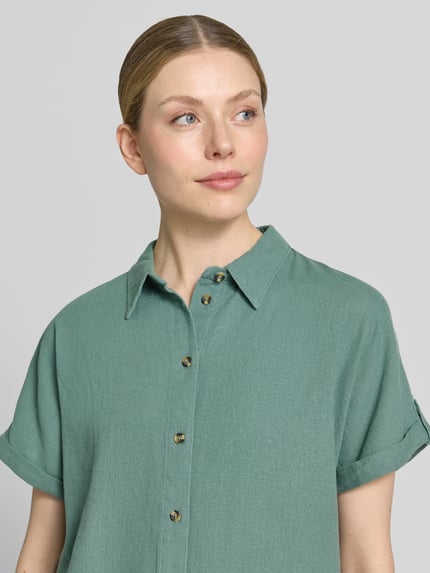 Frauenmodel trägt Relaxed Fit Bluse aus Leinen-Viskose-Mix Modell 'Lava' von FREE/QUENT in hellem Grün, sichtbare Knopfleiste, Nahaufnahme Oberkörper.