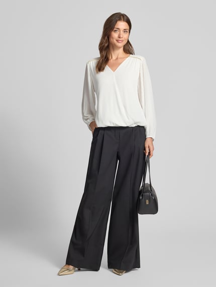 Frauenmodel trägt Bluse mit V-Ausschnitt Modell 'Be44rtaa' von ZABAIONE in Weiß, gerader Schnitt, elastische Abschlüsse, Ganzkörperansicht von vorne.
