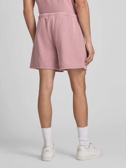 Männermodel trägt Sweatshorts mit Eingrifftaschen von CHAMPION in Rosa, Baumwoll-Mix, Regular Fit, Ganzkörperansicht Rückansicht.
