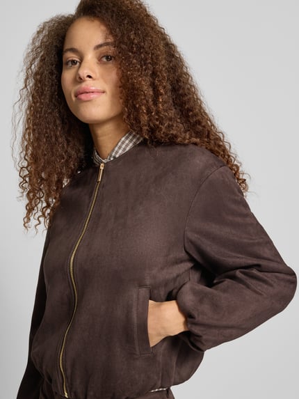 Kobiece model prezentuje Regular Fit Kunstlederjacke in Velourleder-Optik Modell 'STINA' von ONLY, damska kurtka skórzana, ciemnobrązowy kolor, zamek z przodu, matowa tekstura, kontekst: damska kurtka skórzana / kurtka ze skóry ekologicznej od ONLY, zbliżenie na górną część ciała.