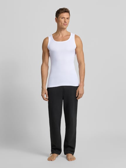 Männermodel trägt Tanktop aus reiner Baumwolle im 2er-Pack von TOM TAILOR mit feiner Rippenstruktur, schmaler Schnitt, Rundhalsausschnitt, weiße Farbe, Ganzkörperansicht von vorne.