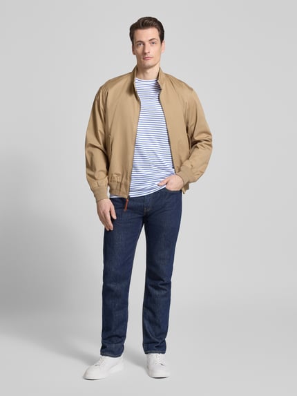 Mannelijk model draagt Regular Fit T-shirt uit puur katoen van Tommy Hilfiger met all-over gestreept motief, ronde hals, korte mouw, logostitching, heren T-shirtlook, regular fit, detailapplicatie, kleur wit-blauw, textuur glad, geheelopname van voren.