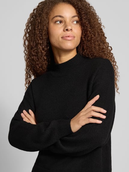 Frauenmodel trägt schwarzen Pullover mit Mock Neck Modell 'PCMALOU' von PIECES, fein gestrickte Struktur, Nahaufnahme Oberkörper.