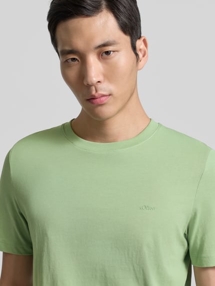 Männermodel trägt Regular Fit T-Shirt aus reiner Baumwolle von s.Oliver RED LABEL in uni Hellgrün, Jersey, Label-Stitching, Nahaufnahme Oberkörper.