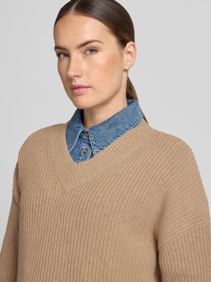 Frauenmodel trägt Loose-Fit Pullover aus Woll-Mix von Marc O'Polo in Beige, grobe Strickstruktur, darüber Jeanshemd, Nahaufnahme Oberkörper, Damen Pullover von Marc O'Polo.