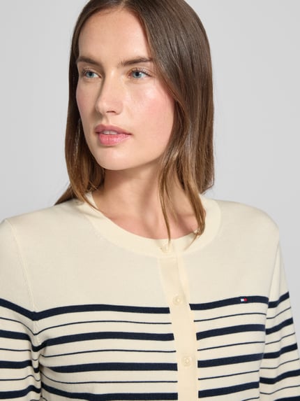 Frauenmodel trägt Regular Fit Strickjacke aus Baumwoll-Mix von Tommy Hilfiger in Creme mit dunkelblauen Streifen, Nahaufnahme Oberkörper.