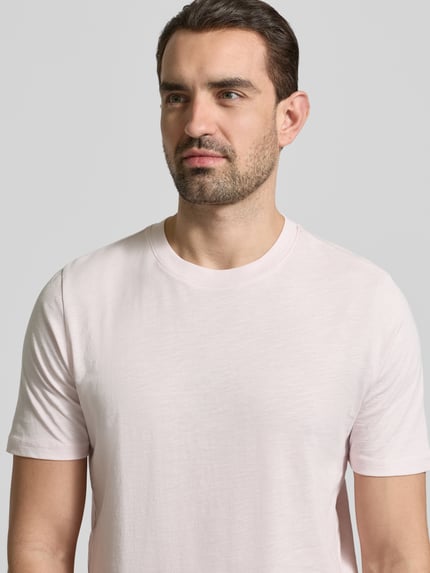 Männermodel trägt Regular Fit T-Shirt mit Rundhalsausschnitt von MCNEAL in Hellrosa, reine Baumwolle, Nahaufnahme Oberkörper.
