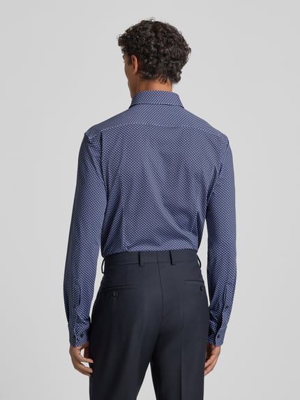 Männermodel trägt Slim Fit Businesshemd mit Kentkragen Modell 'KENNO' von HUGO, Optik: Allover-Muster, Rückenpasse, Ganzkörperansicht Rückansicht.