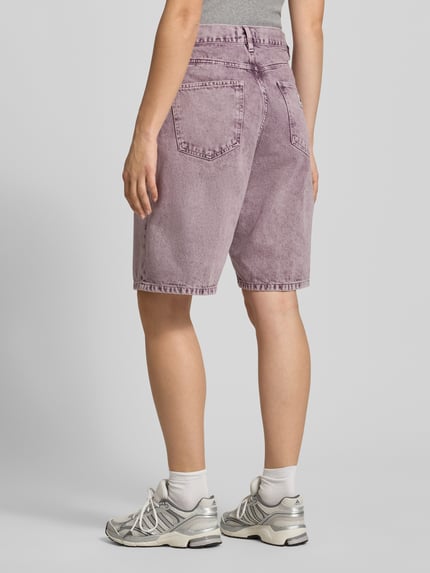 Frauenmodel trägt Straight Fit Jeansshorts im 5-Pocket-Design von Carhartt Work In Progress aus Reine Baumwolle in Lila, Ganzkörperansicht Rückansicht. Bundweite bei Größe S: 40 cm, Innenbeinlänge bei Größe S: 26 cm.