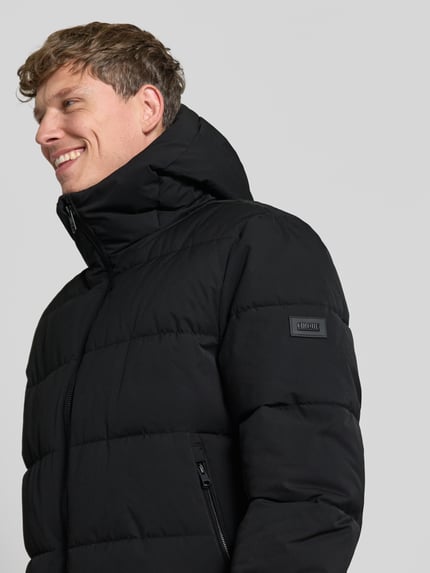 Männermodel trägt schwarzen Steppmantel mit Zweiwege-Reißverschluss Modell 'COMFORT' von CINQUE, Nahaufnahme Oberkörper, glatte Textur.