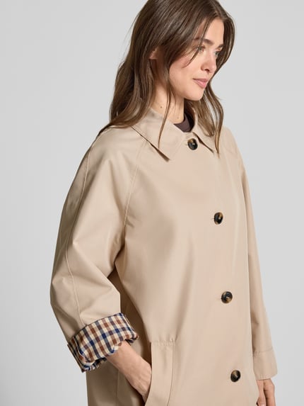 Frauenmodel trägt Taillierter Trenchcoat mit Innenmuster von Jake*s Collection, Material-Mix mit Woll-Anteil, Knopfleiste, Eingrifftaschen, Nahaufnahme Oberkörper.