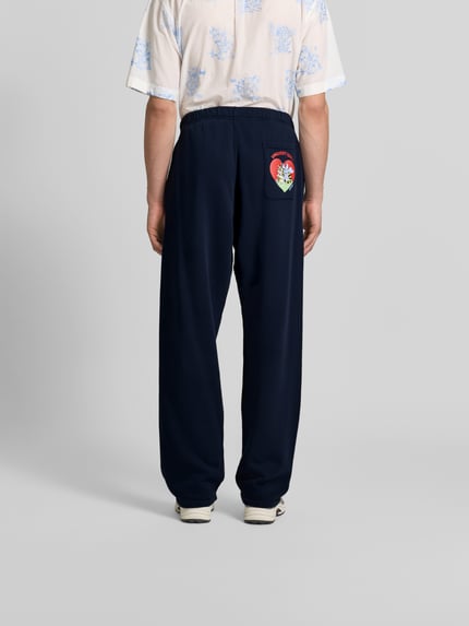Mężczyzna nosi Wide Fit Sweatpants mit Eingrifftaschen von Kenzo z bawełny, wpuszczane kieszenie, elastyczny pas, kieszeń z tyłu, granat, tekstura gładka, długość wewnętrzna nogawki 40 cm, szerokość w rozmiarze M 88 cm, widok całej sylwetki z tyłu.