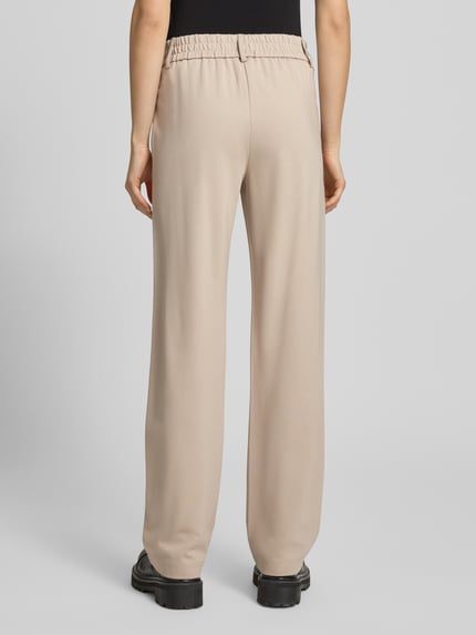Frauenmodel trägt Straight Fit Hose aus Viskose-Mix Modell 'POPTRASH' von Only in Beige mit elastischem Bund und Seitentaschen, Ganzkörperansicht Rückansicht.
