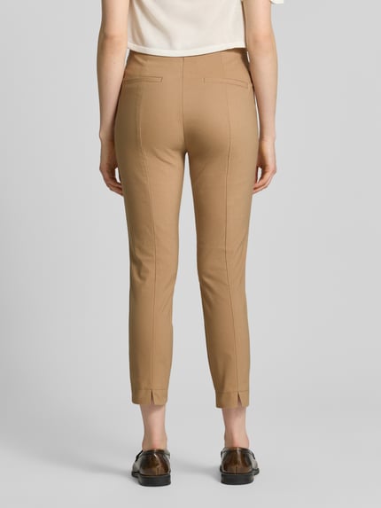 Frauenmodel trägt Slim Fit Stoffhose in verkürzter Passform von Christian Berg Woman in hellem Braun, glatte Struktur, Ganzkörperansicht Rückansicht, elastischer Baumwoll-Mix, Bundweite 39 cm, Innenbeinlänge 66 cm.