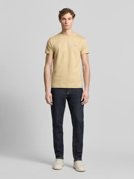 Mannelijk model draagt T-Shirt met Label-Detail van Gant in recht model, ronde hals, zuiver katoen, zandkleur, vooraanzicht volledige lichaam.