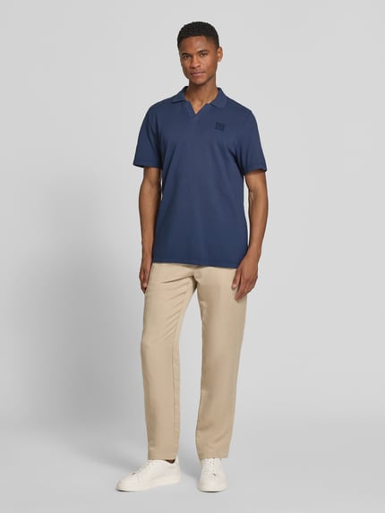 Männermodel trägt Regular Fit Poloshirt aus reiner Baumwolle von s.Oliver RED LABEL in Dunkelblau, unifarben, Ganzkörperansicht von vorne.
