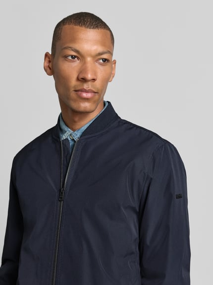 Männermodel trägt Regular Fit Jacke mit Stehkragen Modell 'Rapid' von CINQUE, marineblau, glatte Oberfläche, Nahaufnahme Oberkörper. Herren Jacke von CINQUE, Zweiwege-Reißverschluss, elastische Abschlüsse, Eingrifftaschen, Rückenlänge 70 cm, Schulterbreite 49 cm, Brustweite 59 cm, Ärmellänge 69 cm.