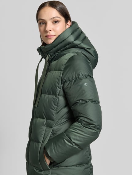Vrouwenmodel draagt Regular Fit lange donsjas met labelprint van Marc O'Polo in donkergroen, gladde textuur, zijaanzicht, Dames Daunenmantel von Marc O'Polo, Nahaufnahme Oberkörper.