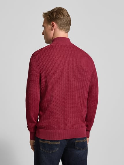 Mężczyzna nosi Strickjacke mit Reißverschluss od Christian Berg Men w kolorze bordowym, z prążkowaną fakturą, Slim Fit, widok całej sylwetki od tyłu.
