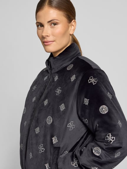 Modelka kobieca nosi Jacke im Allover-Look Modell 'AMALIA' od GUESS Activewear, czarny materiał z ozdobnymi kamieniami, krój regular fit, mieszanka materiałów z dodatkiem stretchu, stójka, zamek błyskawiczny, zbliżenie na górną część ciała.