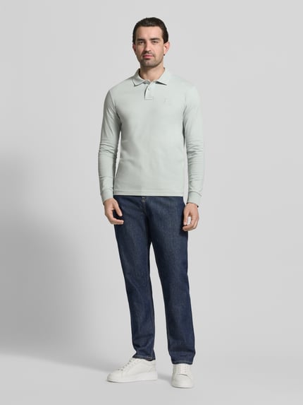 Männermodel trägt Slim Fit Poloshirt aus katoenmix Modell 'PASSERBY' van BOSS Orange in effen optiek, piqué textuur, voorkant volledige lichaamsweergave.