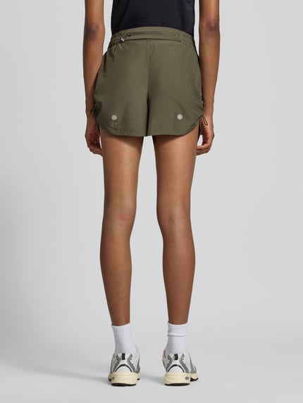 Vrouwenmodel draagt korte broek met elastische band Model 'NAGINO' van ASICS TIGER, recht pasvorm, reflecterende details, ritszak achter, zij-steekzakken, bandwijdte maat S 34 cm, binnenbeenlengte maat S 14 cm, geheel achteraanzicht