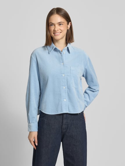 Vrouwenmodel draagt Relaxed Fit Hemdbluse aus reiner Baumwolle van Marc O'Polo Denim in effen lichtblauw corduroy met borstzak, lange mouw, afgeronde rompzoom; vooraanzicht, bovenlichaam close-up.