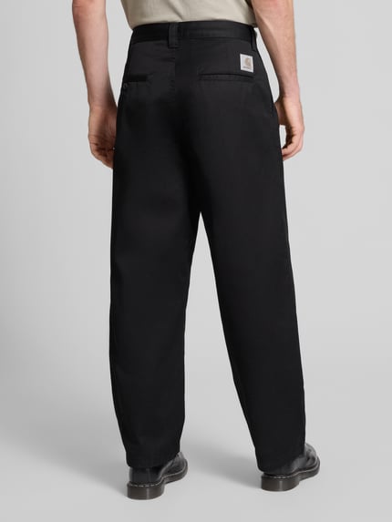 Męski model nosi Chino mit Gesäßtaschen Modell 'BRADY' od Carhartt Work In Progress, czarny, luźny krój, bawełna, widok całej sylwetki od tyłu. Szerokość w rozmiarze M: 44 cm, długość nogawki: 75 cm.