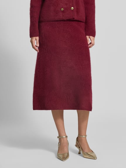 Vrouwenmodel draagt Wollrock met elastischem Bund van Christian Berg Woman in bordeaux, zuiver wol, recht model, Midirok, detailopname onderlichaam. Bandwijdte maat S: 35 cm, totale lengte maat S: 80 cm.