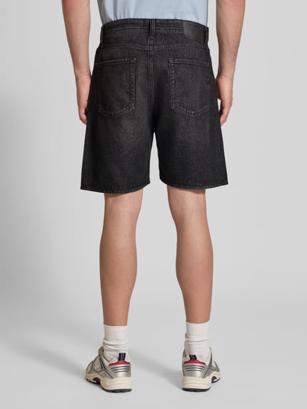 Männermodel trägt Loose Fit Jeansshorts mit Eingrifftaschen Modell 'TONY' von Jack & Jones, schwarze Used-Optik, reine Baumwolle, Ganzkörperansicht Rückansicht.