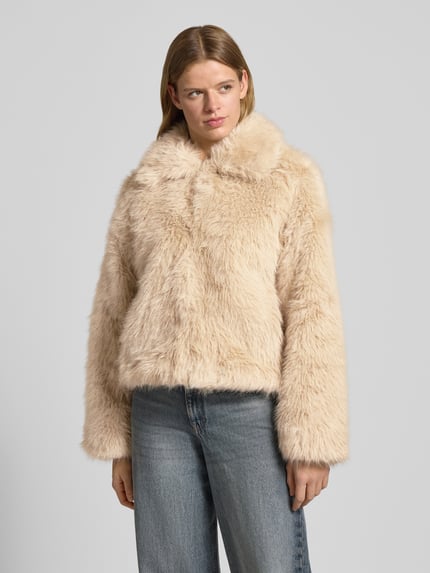 Vrouwenmodel draagt Jacke uit imitatiebont Model 'EVIE' van Noisy May, regular fit met platte kraag, beige, textuur zacht, Ganzkörperansicht von voren. Ruglengte maat S 68 cm, schouderbreedte 52 cm, borstwijdte 55 cm, mouwlengte 60 cm.