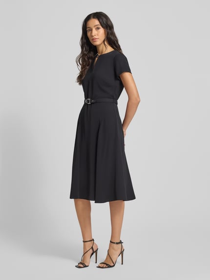 Kobiece model prezentuje Knielanges Kleid mit Taillengürtel von Lauren Ralph Lauren, czarny kolor, taliowany krój, długość do kolan, wycięcie w kształcie łezki, pasek w talii, wszyty zamek błyskawiczny, długość tyłu 99 cm, szerokość klatki piersiowej 34 cm, długość rękawów 14 cm, całkowity widok z przodu.