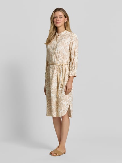 Vrouwenmodel draagt Tunikakleid aus Leinen-Viskose-Mix van Fynch-Hatton in beige met bladmotief, getailleerde pasvorm, midi-jurk, knoopsluiting, strikceintuur en 3/4-mouwen, ruglengte maat 36: 107 cm, borstwijdte maat 36: 51 cm, mouwlengte maat 36: 51 cm, geheelbeeld vooraanzicht.