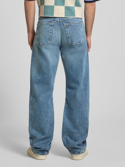 Männermodel trägt Regular Fit Jeans aus reiner Baumwolle von Calvin Klein Jeans, denim blau, 5-pocket-design, label patch, gürtelschlaufen, knoopsluiting, ganzkörperansicht rückansicht.