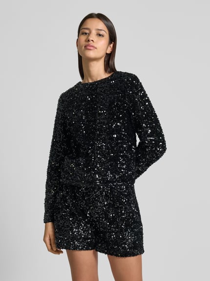 Frauenmodel trägt Regular Fit Langarmshirt mit Pailletten Modell 'CONFIDENCE' von Only, schimmernder Samt, U-Boot-Ausschnitt, Ganzkörperansicht von vorne.