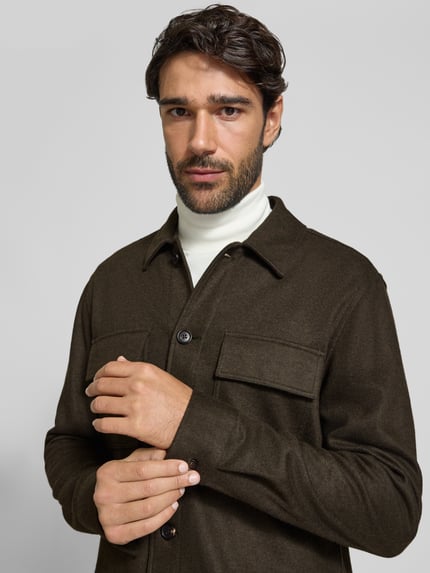 Mężczyzna nosi Regular Fit Hemdjacke mit Kentkragen und Brusttaschen od Profuomo, materiał z domieszką wełny, kolor ciemnobrązowy, z kieszeniami na piersi i zapięciem na guziki, długość tyłu w rozmiarze M: 76 cm, zbliżenie na górną część ciała z przodu.