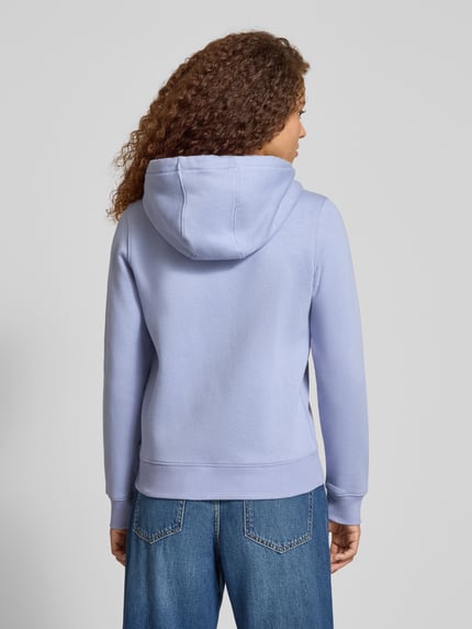 Modelka kobieca nosi Regular Fit Sweatjacke aus Baumwoll-Mix od Tommy Jeans w kolorze jasnofioletowym, widok całej sylwetki od tyłu.