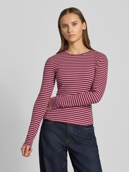 Frauenmodel trägt Slim Fit Langarmshirt mit Rundhalsausschnitt von REVIEW, elastischer Baumwoll-Mix, lila-rosa gestreift, Ganzkörperansicht von vorne.