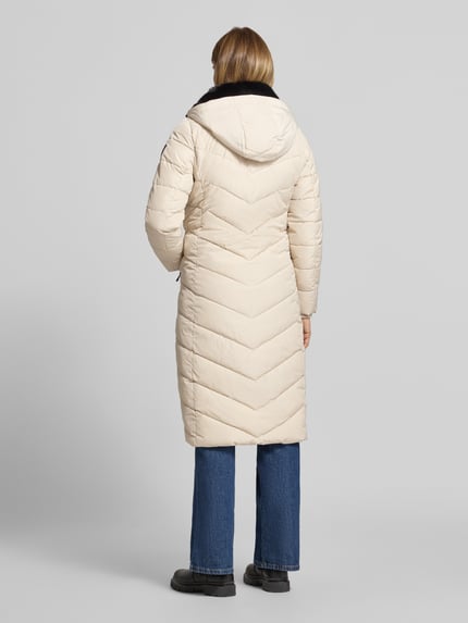Frauenmodel trägt Steppmantel mit Kapuze von NAUTGÅRD 'NEBULA' in Beige, strukturierte Oberfläche, Regular Fit, Ganzkörperansicht Rückansicht. Rückenlänge, Schulterbreite, Brustweite und Ärmellänge entsprechen Größe S. Verdeckter Reißverschluss und Reißverschlusstaschen sichtbar.