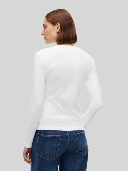 Frauenmodel trägt Slim Fit Langarmshirt aus reiner Baumwolle von Tommy Hilfiger in Weiß, glatte Struktur, blaue Jeans, Ganzkörperansicht Rückansicht, Damen Langarmshirt von Tommy Hilfiger.