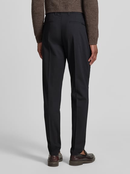 Männermodel trägt dunkelgraue Tapered-Fit Weite Hose 'MOROT JOGGER' von Marc O'Polo × DFB Travel Collection, Herren, Ganzkörperansicht Rückansicht.
