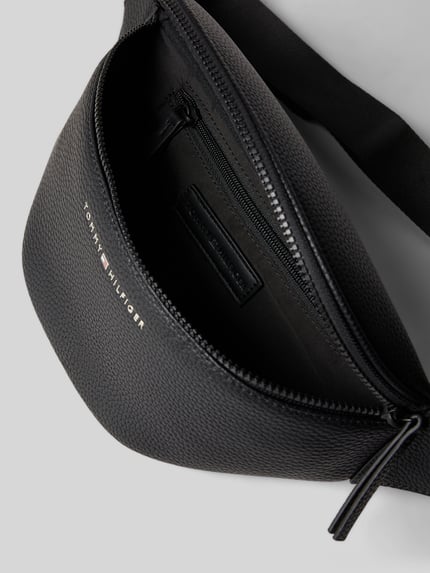 Produktfoto, Bauchtasche mit Strukturmuster von Tommy Hilfiger in Schwarz, robustes Material, Hauptfach mit Reißverschluss, Label-Schriftzug, Logo-Details, Reißverschlussfach innen, verstellbarer Schulterriemen mit Klickverschluss, Maße: Breite 36 cm, Länge 15 cm, Tiefe 5 cm, Schulterriemenlänge 90 cm.