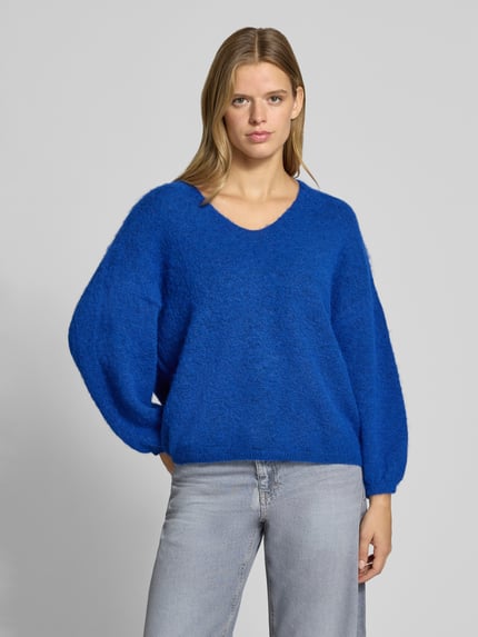 Frauenmodel trägt Pullover mit V-Ausschnitt Modell 'PCALLIE' von PIECES, blau meliert, Strick, elastische Bündchen, Ganzkörperansicht von vorne.