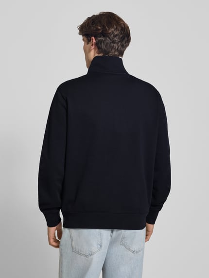 Męski model nosi Regular Fit Sweatshirt aus reiner Baumwolle od Levi's®, czarna bluza, jasnoniebieskie spodnie, całkowity widok z tyłu.
