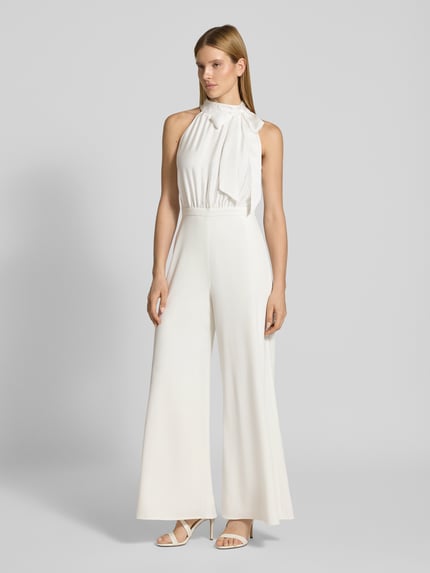 Frauenmodel trägt Jumpsuit mit Schleifen-Applikation von SWING in Weiß, taillierter Schnitt, weite Beine, Neckholder, Ganzkörperansicht von vorne.